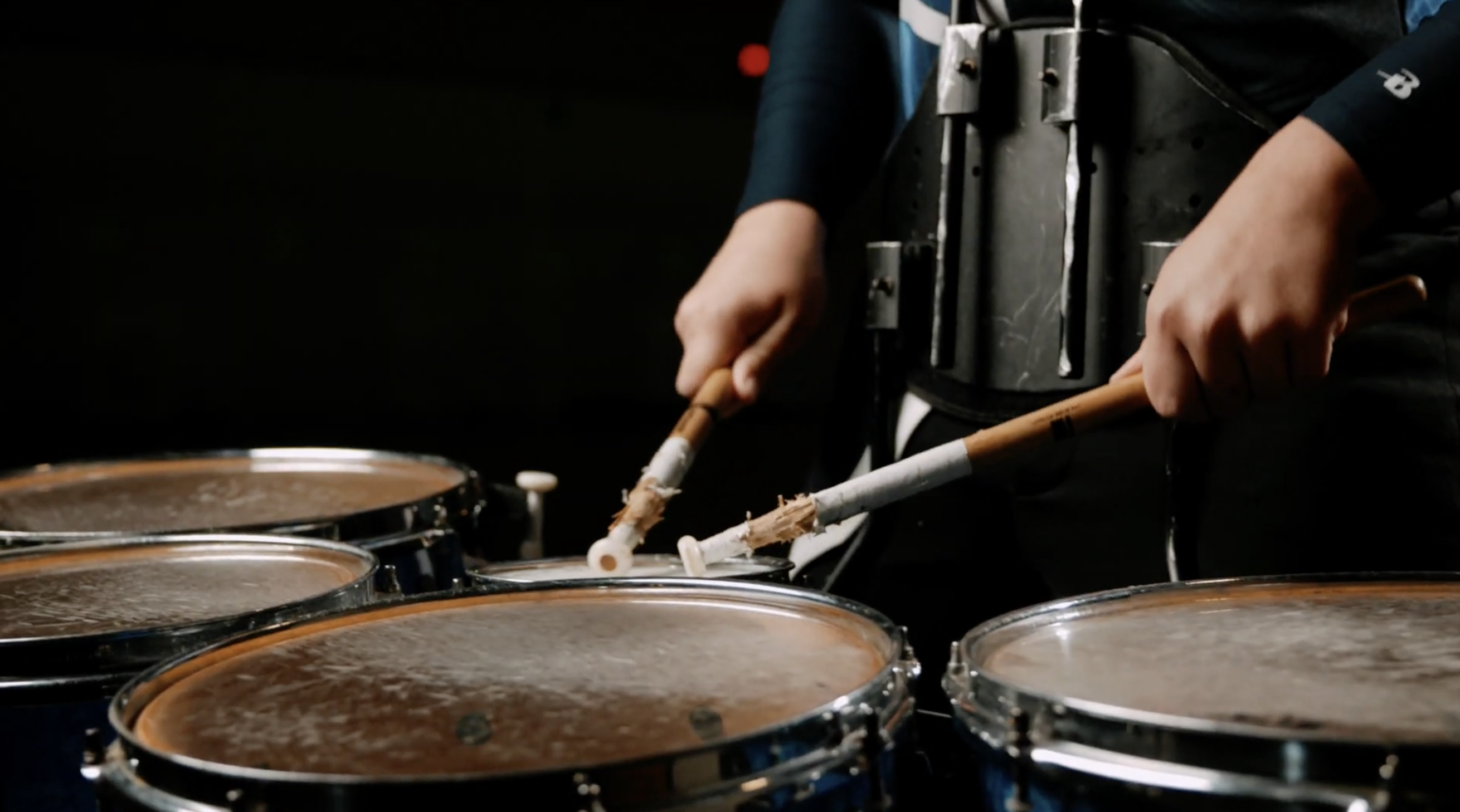 Drummer holding drum sticks and playing drums.